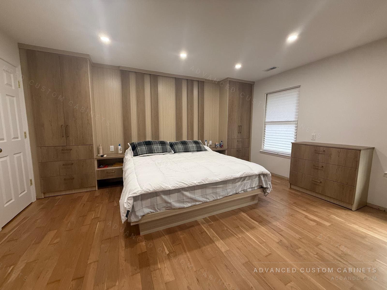 Custom bedroom wall with tall wardrobe towers, built-in nightstands, a slatted headboard panel, a platform bed and a matching dresser