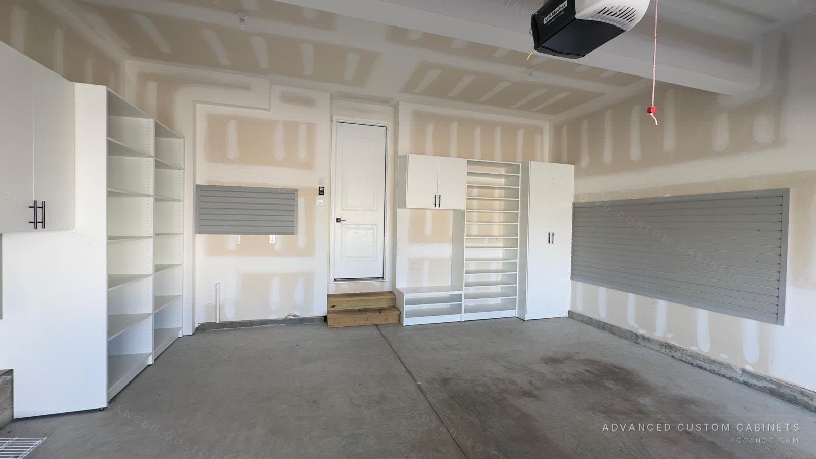 Custom garage storage system with white cabinets, a tall open shelving tower, and gray slatwall organizer panels