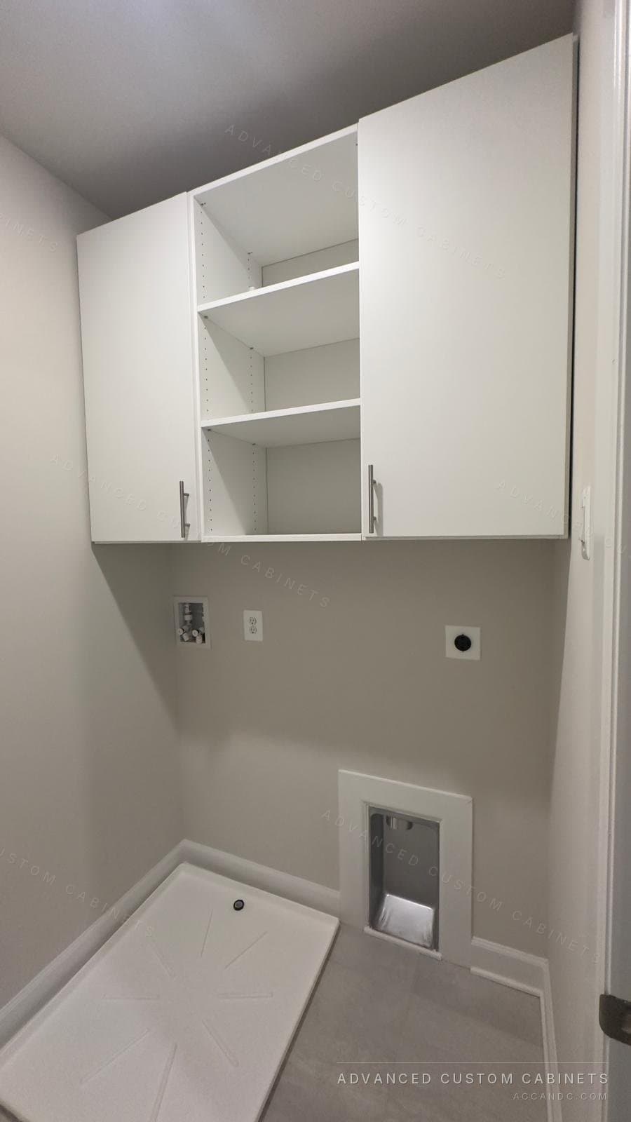 White laundry room upper cabinets with chrome pulls above the washer and dryer hookups