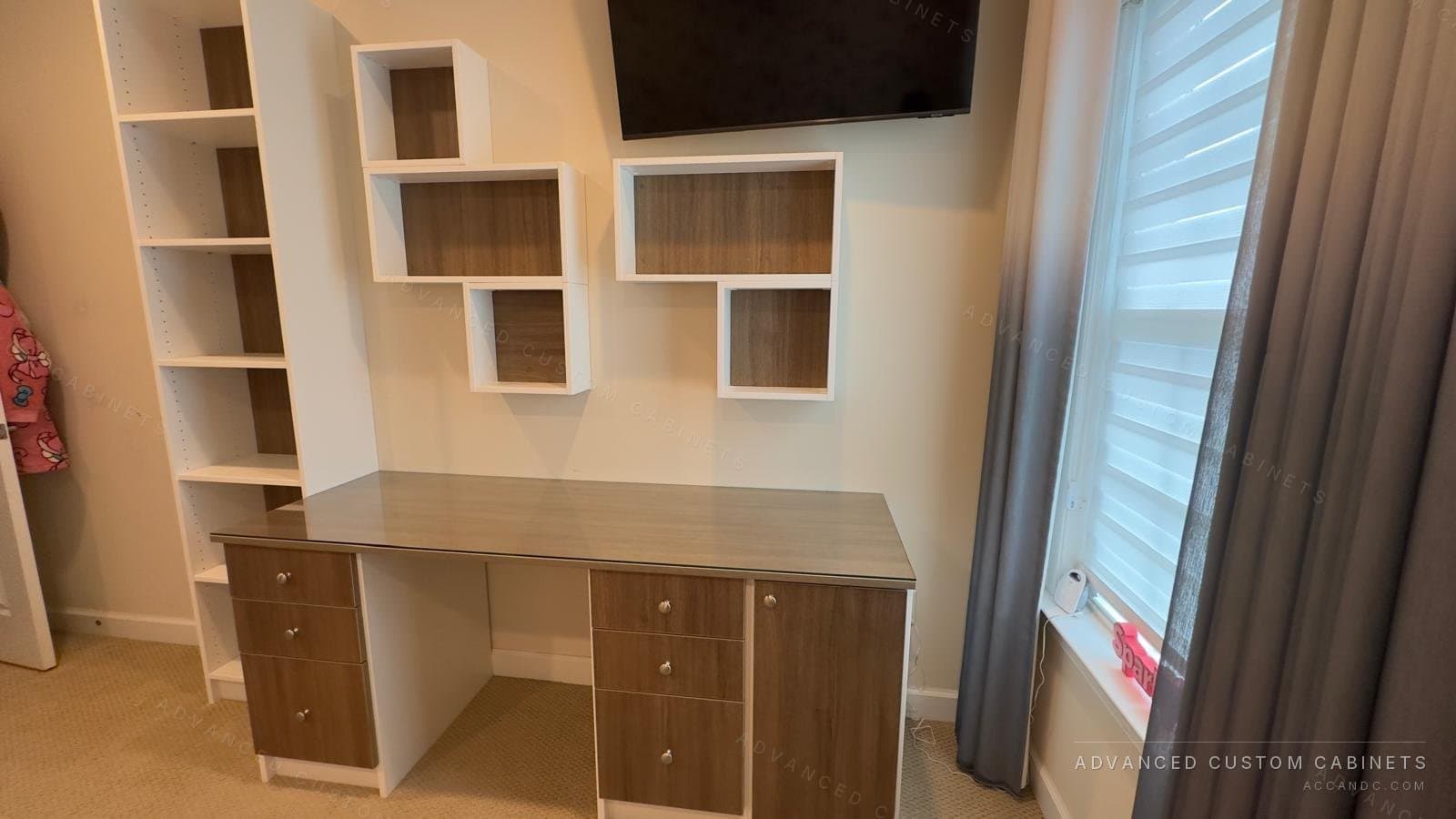 Custom home office built-in with two-tone desk, glass top, tall bookcase shelving and wall-mounted display cubes