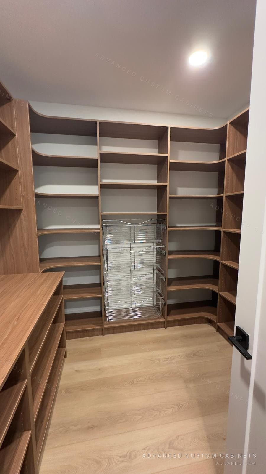 Custom walk-in pantry with floor-to-ceiling wood shelving, curved corner shelves, and pull-out wire basket drawers