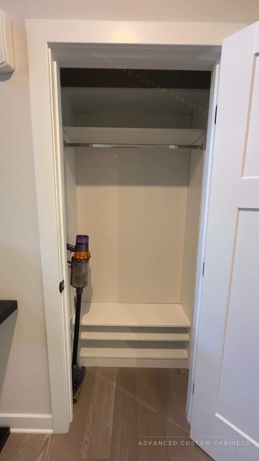 White reach-in closet with a hanging rod under a deep top shelf and a raised two-tier shoe shelf at the floor