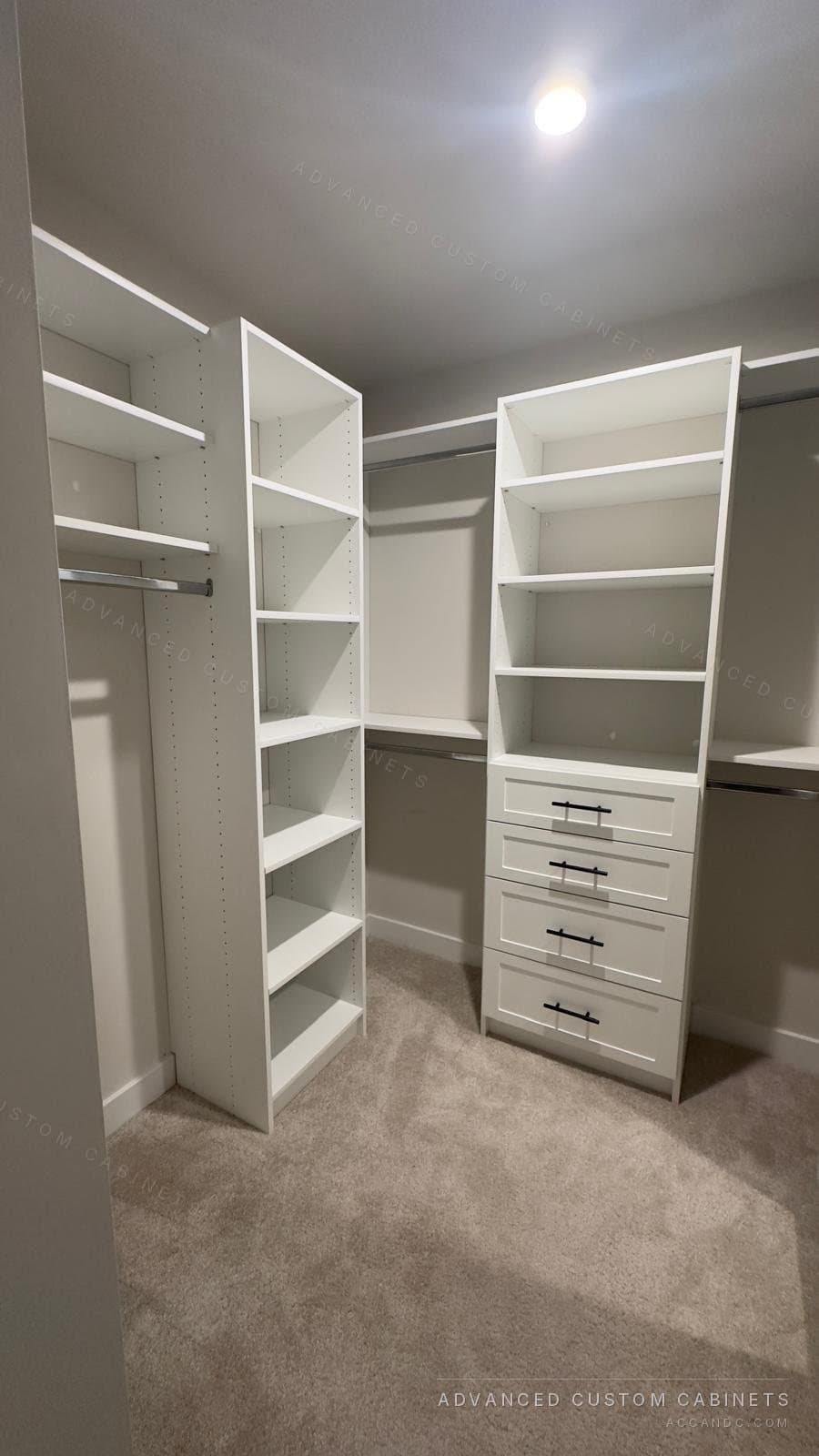 Custom white walk-in closet with corner shelf tower, four-drawer base with black bar pulls, and chrome hanging rods over neutral carpet