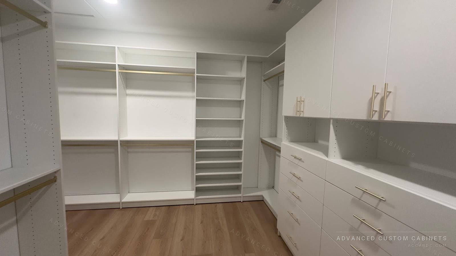 Custom white walk-in closet with adjustable shelving, brass rods, a drawer tower, and tall cabinets