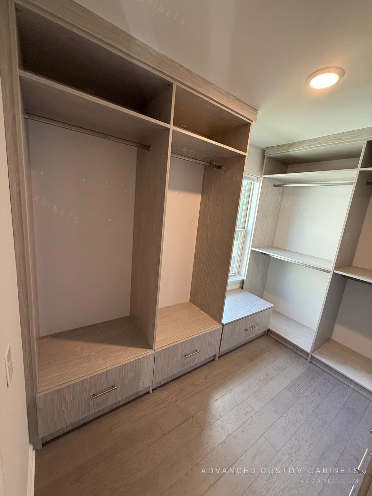 Grey-oak walk-in closet with a window seat, drawer bases and hanging sections on three walls