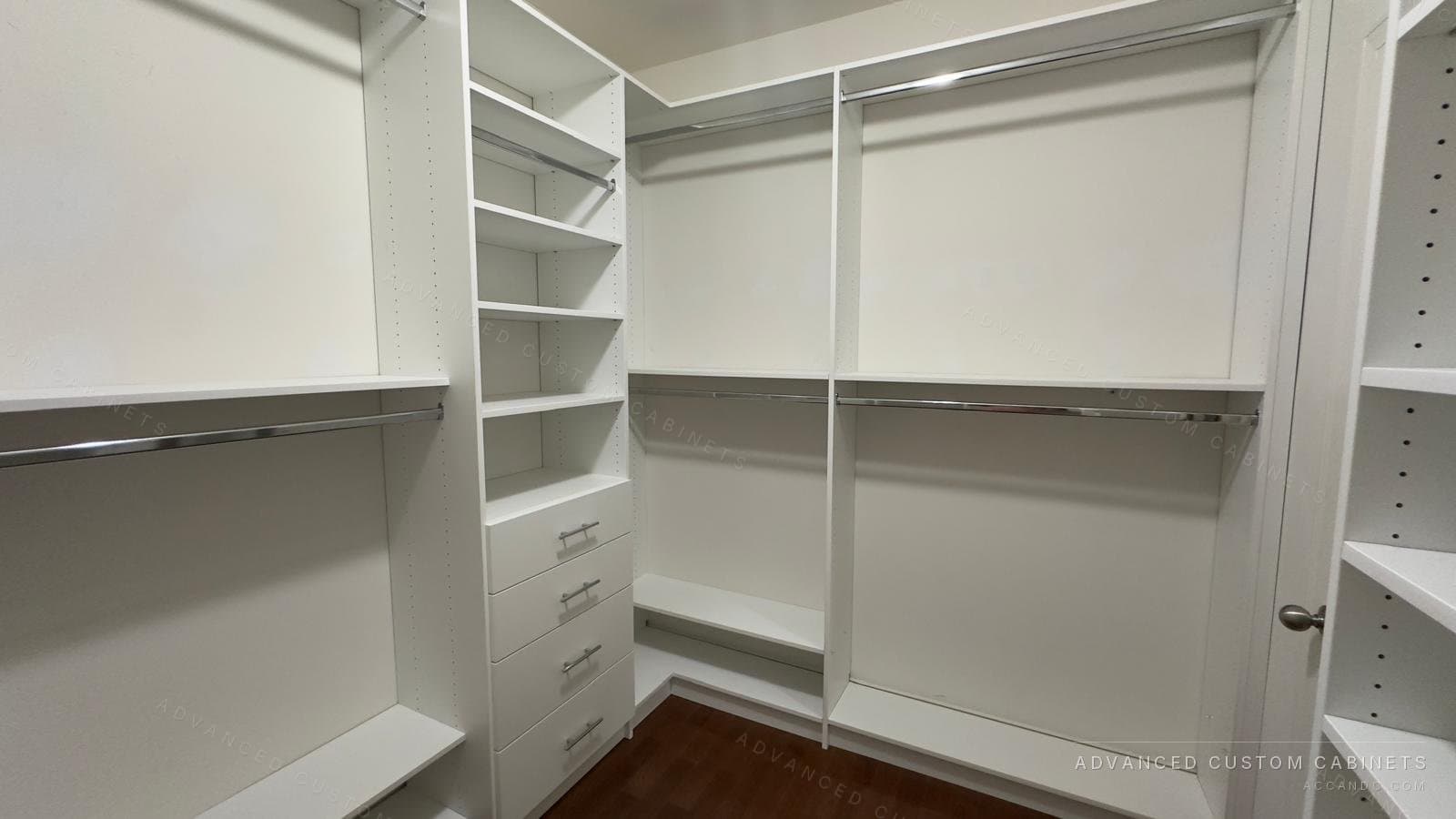 Custom white walk-in closet with double hanging along the walls, a shelving tower over a four-drawer base, and chrome rods