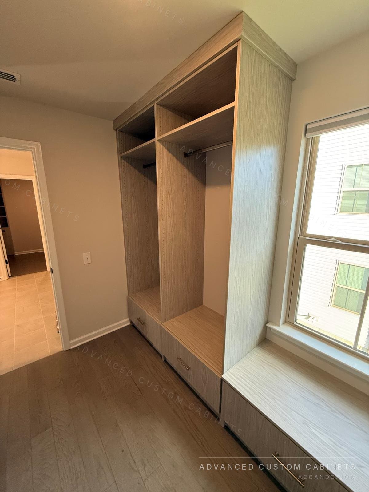 Grey-oak walk-in closet with a window bench between two hanging sections