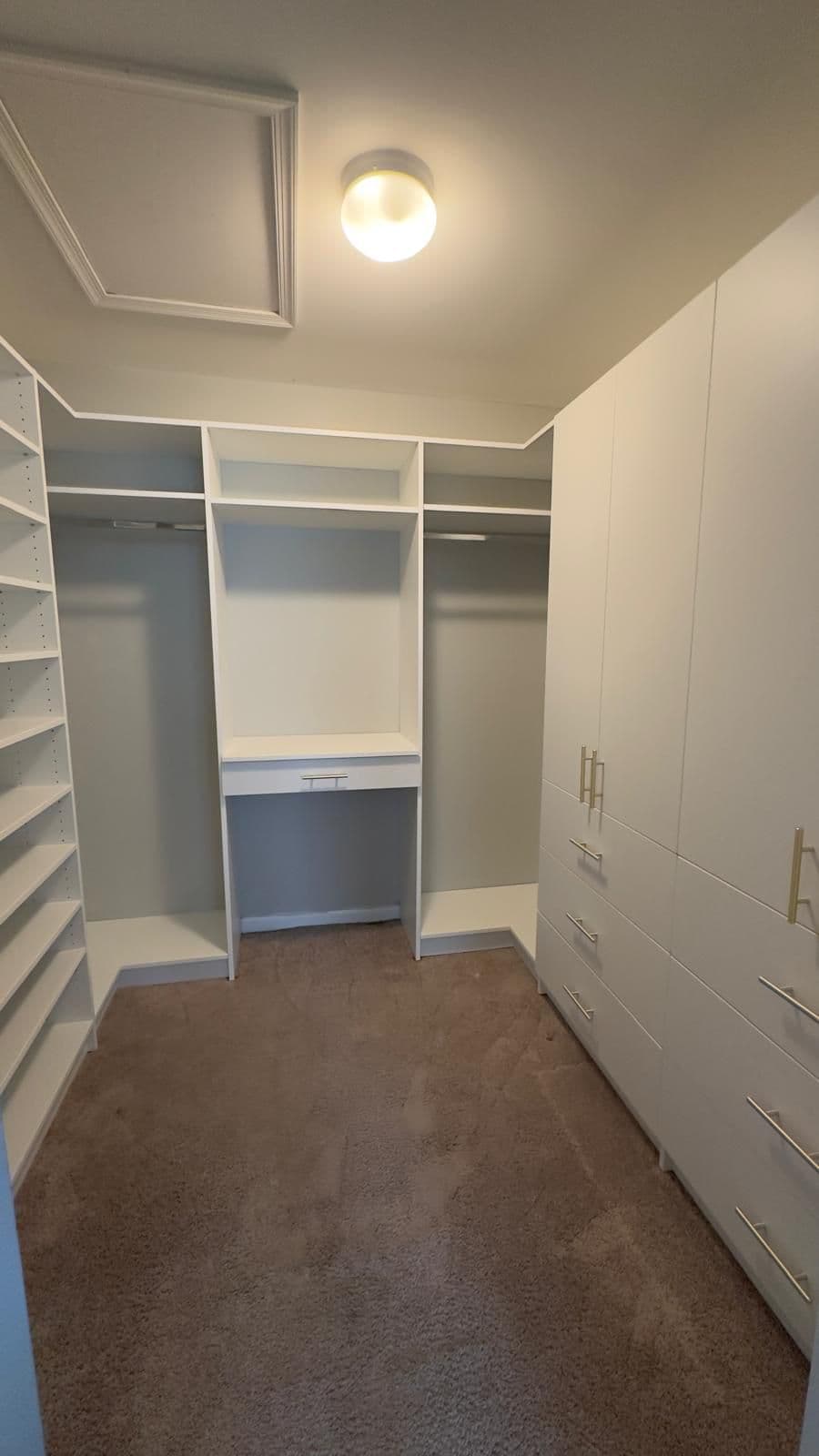 Custom white walk-in closet with gray-accent shelving, built-in desk and drawer base