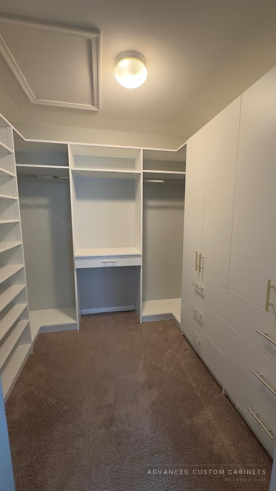 Custom white walk-in closet with gray-accent shelving, built-in desk and drawer base