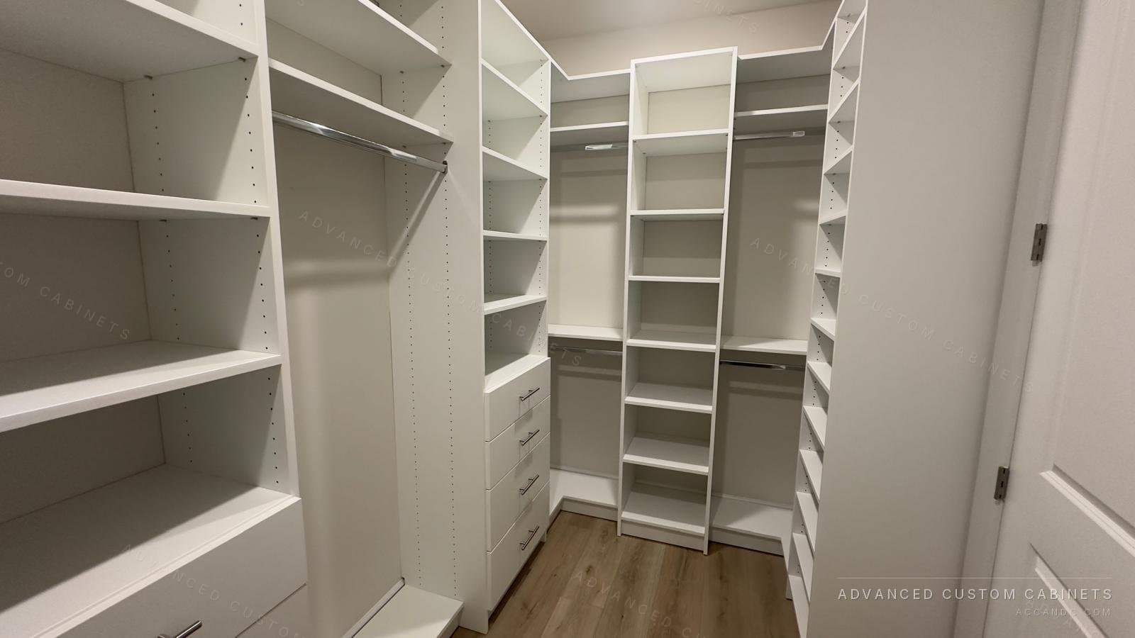 White walk-in closet with floor-to-ceiling shelving, angled shoe shelves and hanging sections on three walls
