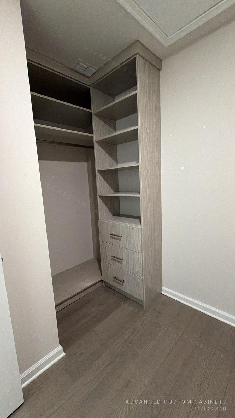Grey-oak closet section with adjustable shelves over a three-drawer base in a corner niche