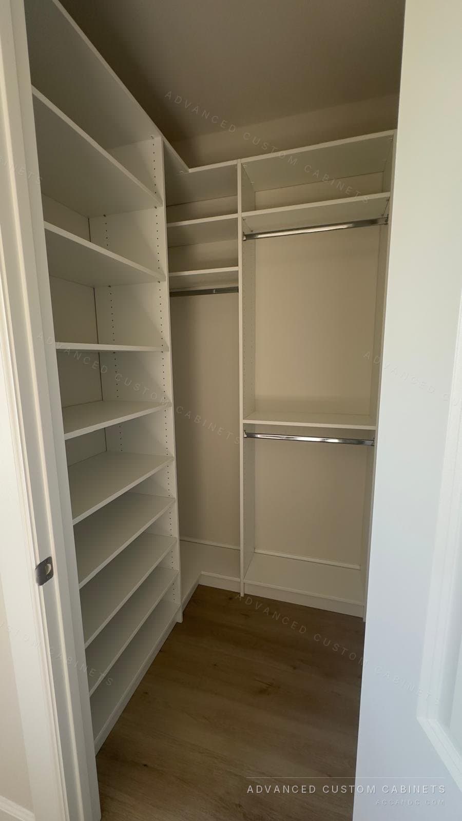 Narrow white walk-in closet with a full-height shelving column and double hanging rods