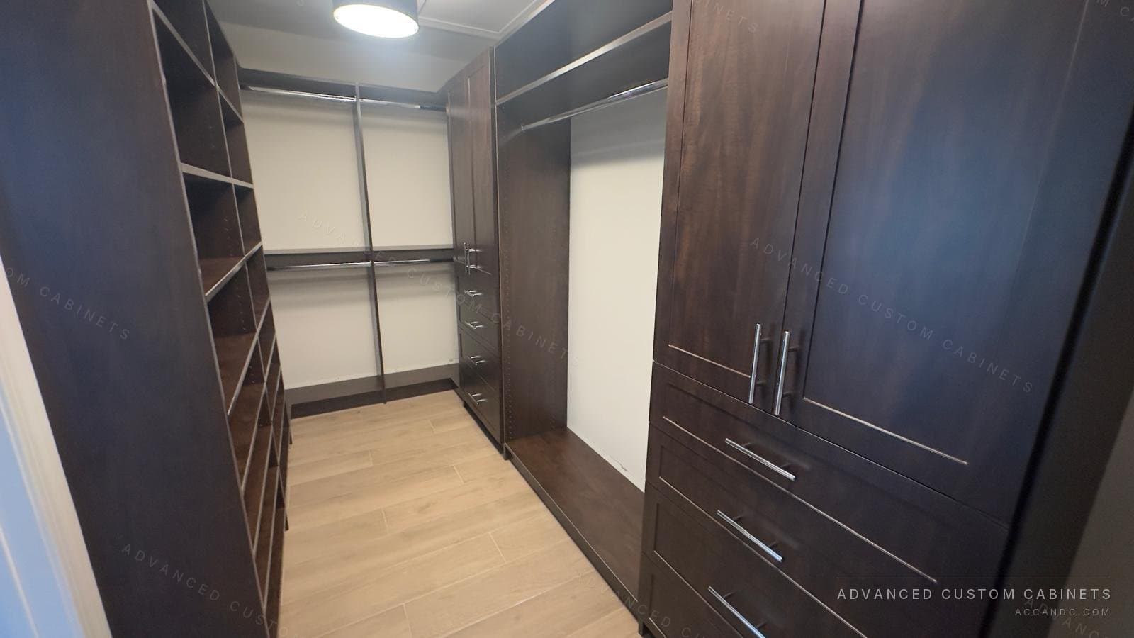 Espresso-finish custom walk-in closet with tall cabinet doors, open corner shelving, and hanging sections