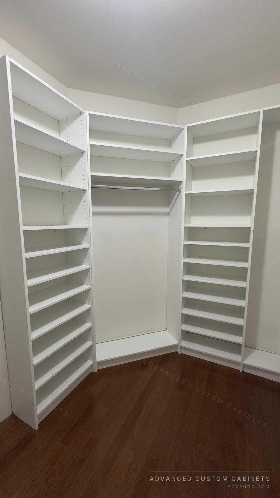 Custom white walk-in closet corner with tall shoe shelving towers on both sides and a center hanging section under an upper shelf