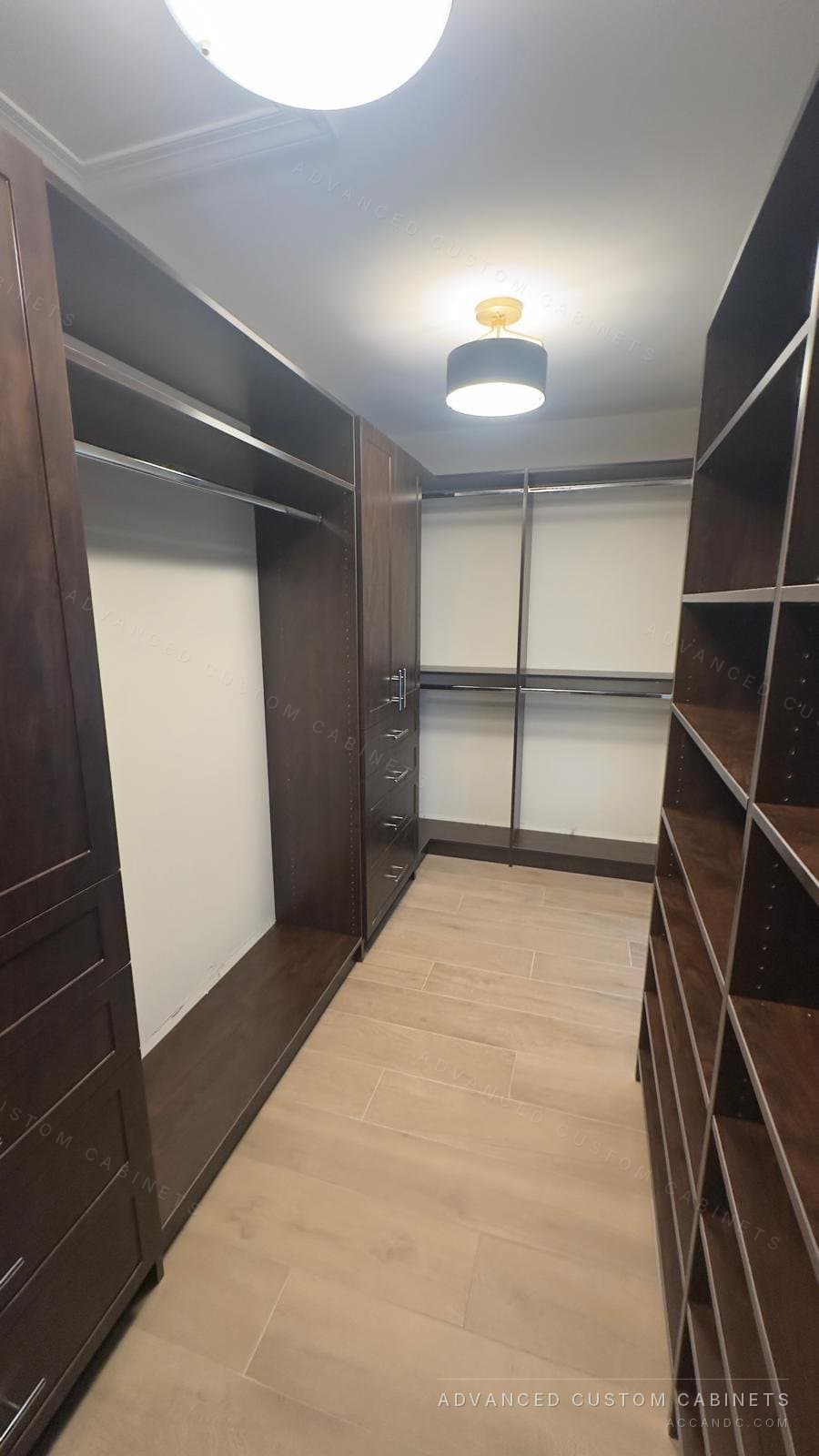 Dark wood custom walk-in closet with floor-to-ceiling shelving on both walls and hanging rods down the centre