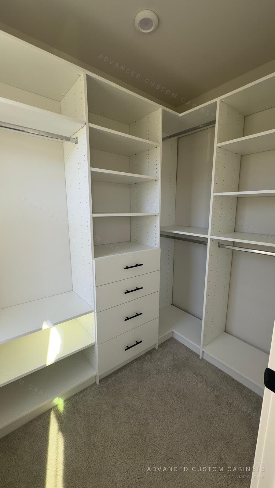 Sunlit white walk-in closet with a long-hang section over open shelves, a shelving tower over four drawers and double hanging in the corner