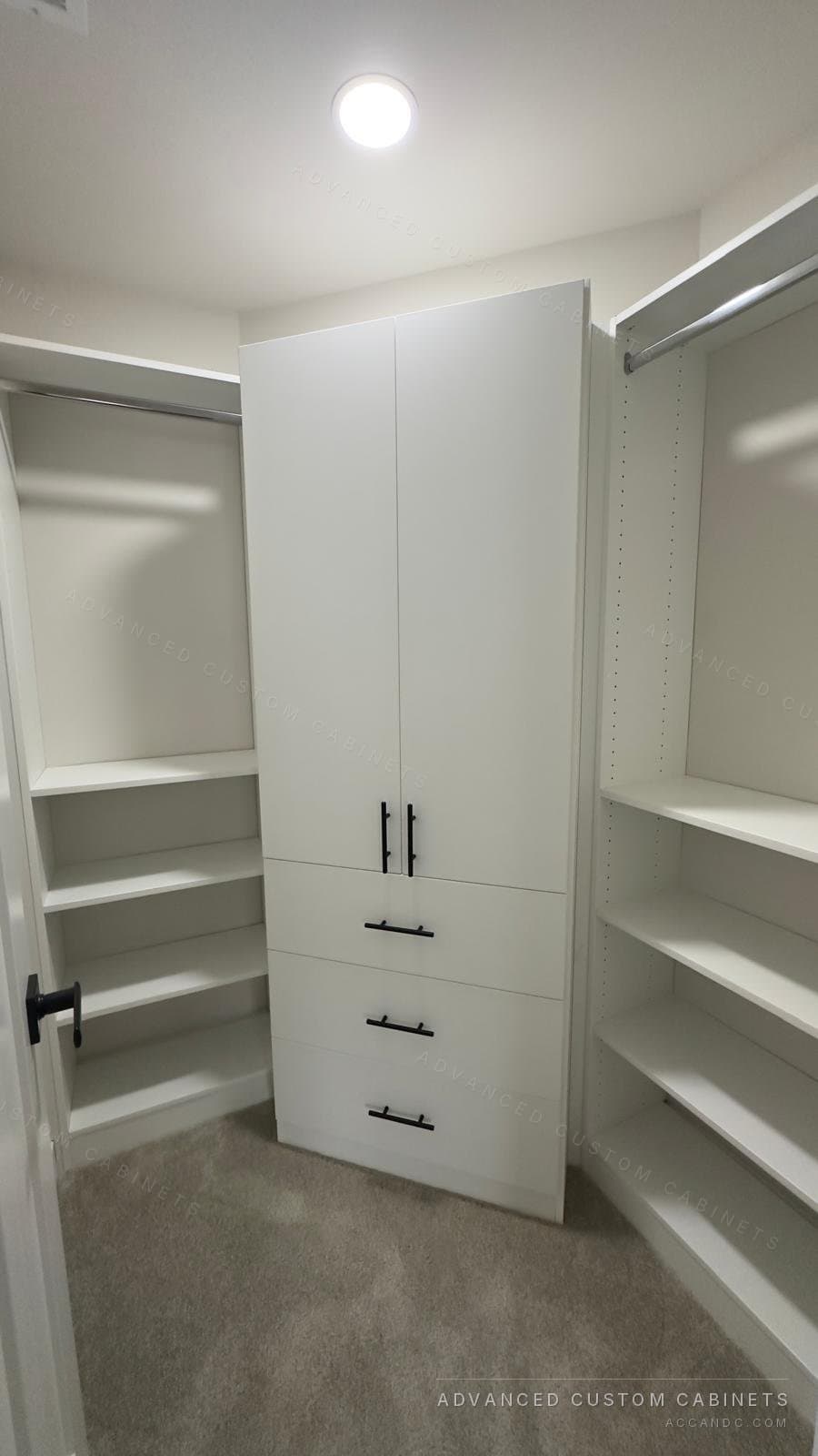 White walk-in closet with a full-height door cabinet over drawers, open shelves and hanging sections on both walls