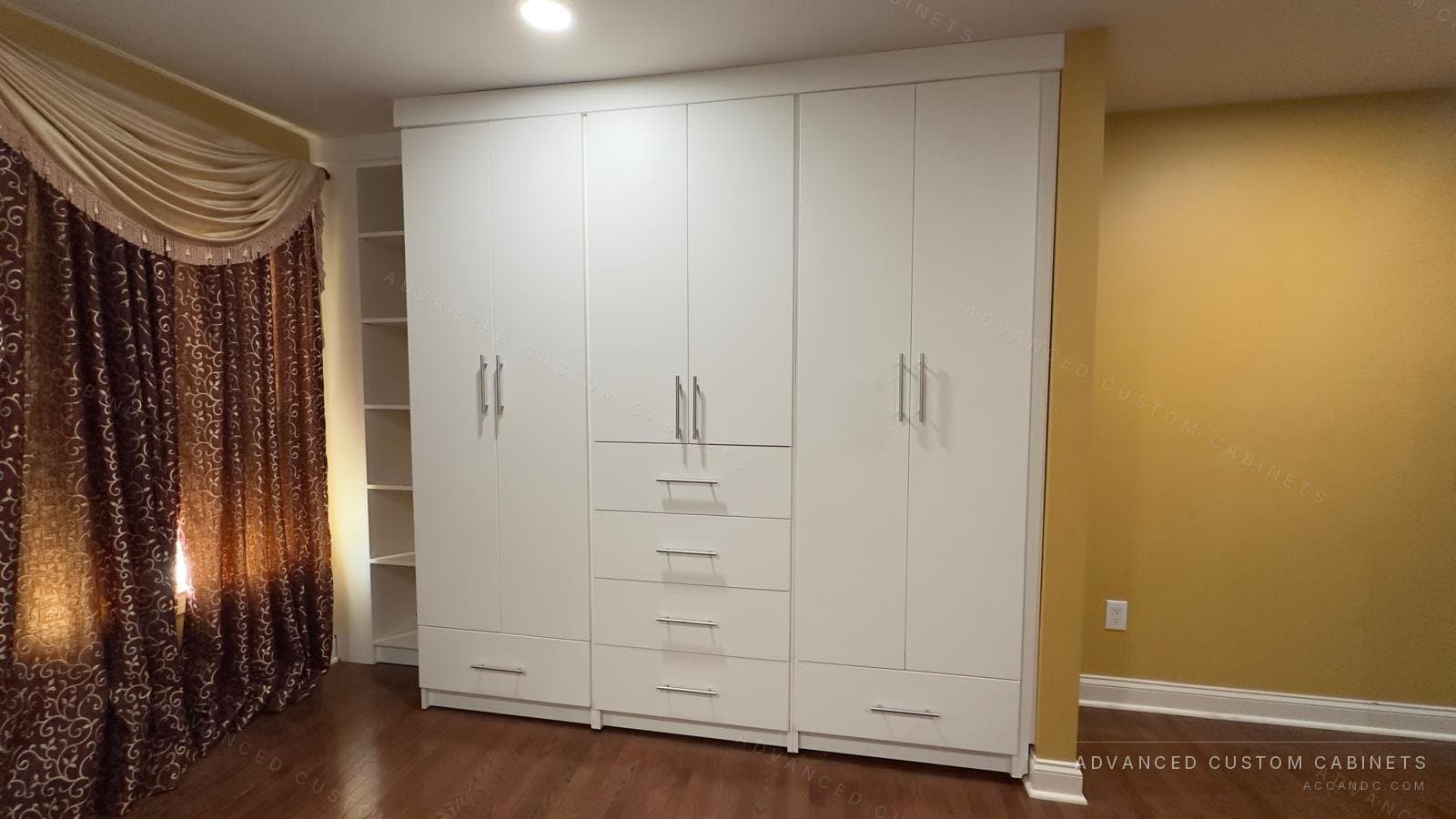 White wardrobe wall with a narrow drawer tower between two door sections and open corner shelving alongside