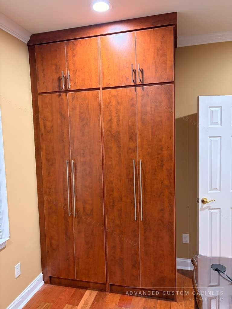Custom floor-to-ceiling wardrobe in cherry wood finish with bar-pull handles
