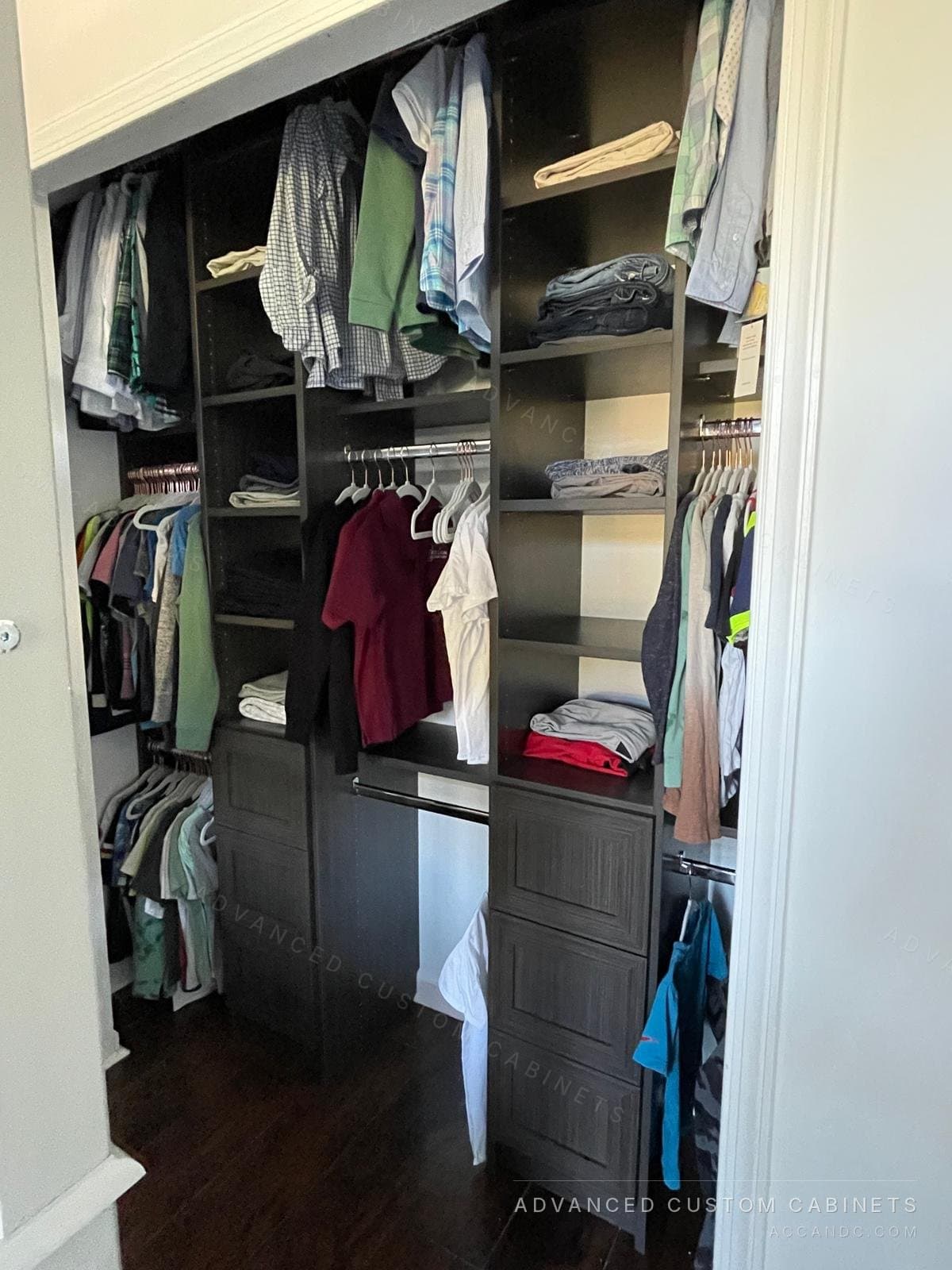 Dark espresso reach-in closet with central tower, drawers, and full-length hanging