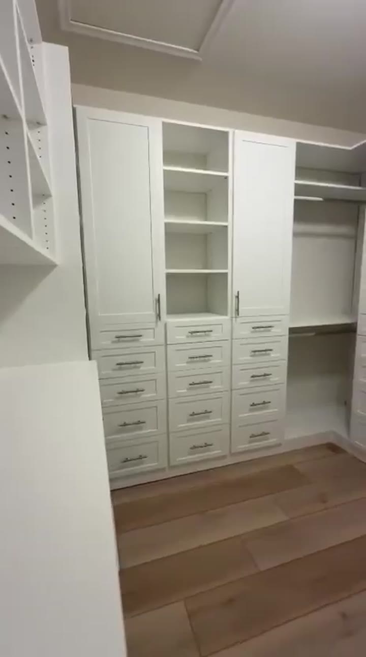 White walk-in closet with shaker drawer banks under tall doors, open shelf towers and double hanging in the corner, video walkthrough